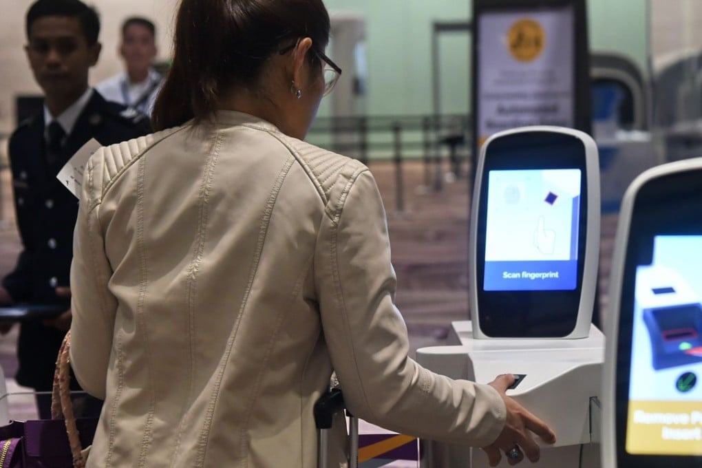 A passenger scans her thumb on an automated immigration gate at the newly-opened Changi International Airport Terminal 4 in Singapore. Photo: AFP