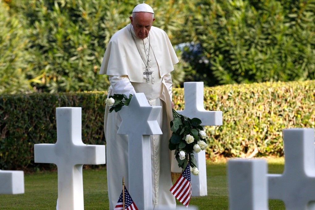 Pope Francis leaves a white rose on the grave of US sergeant Bernard Braverman before a mass at the US World War II cemetery on the day Christians around the world commemorate their dead, in Nettuno, near Rome, on November 2, 2017. Photo: Agence France-Presse