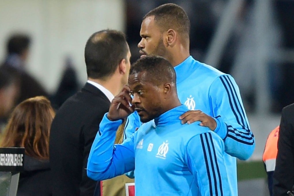 Marseille defender Patrice Evra is escorted off the pitch by teammates after an argument with supporters before their Europa League match against Vitoria. Photo: AFP