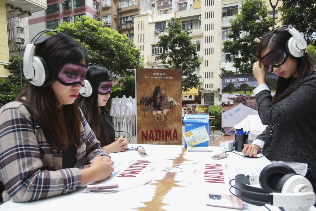The UN Refugee Agency has set up three tables with headphones and eye masks on Lee Tung Avenue in Wan Chai, where listeners can learn more about the plight of refugees. Photo: Edmond So