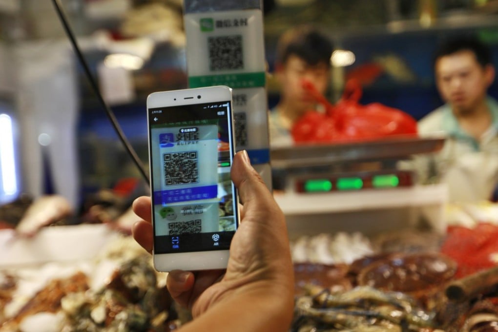 A customer scans an Alipay QR code to make a payment via a mobile phone in a market in Beijing in August. The mobile payment revolution is sweeping the globe because of its tremendous convenience. Photo: EPA