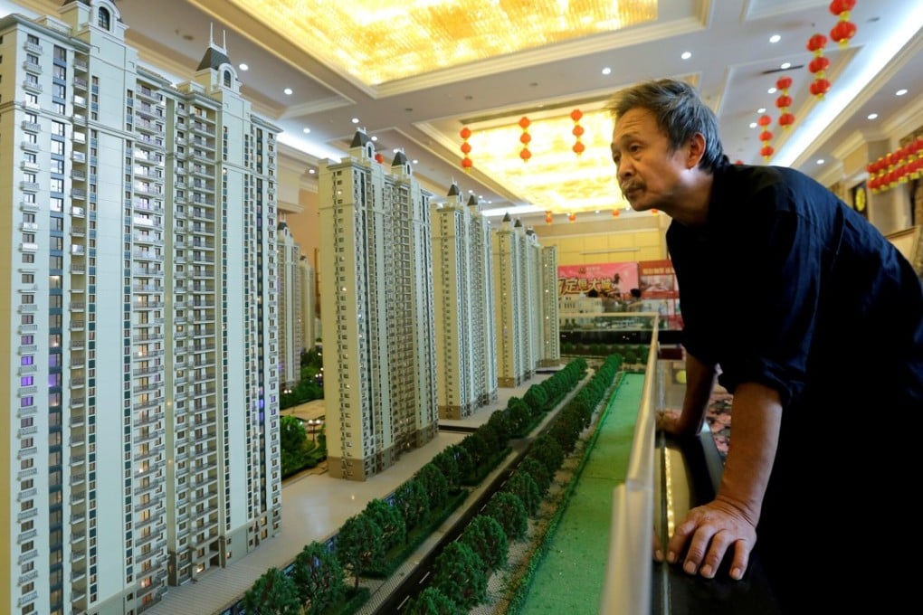 A visitor looks at a model of a new apartment complex at a showroom of Evergrande Real Estate Group. The company is planning to list its property arm on the Shenzhen stock exchange. Photo: Reuters
