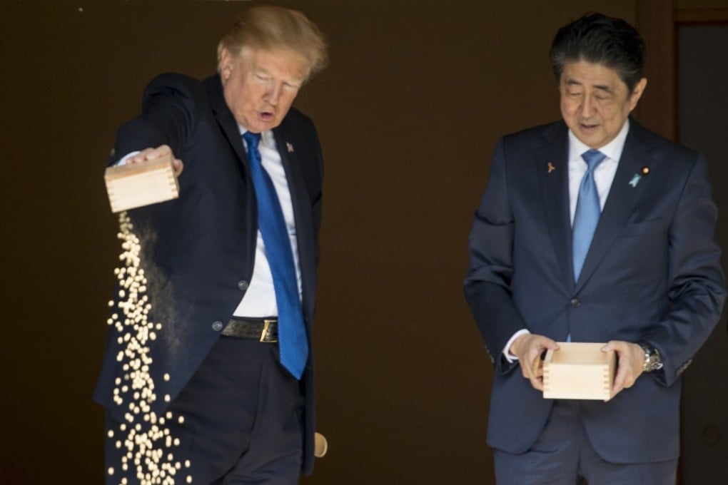 US President Donald Trump pours the remainder of his fish food out as he and Japanese Prime Minister Shinzo Abe feed fish in a koi pond at the Akasaka Palace. Photo: AP