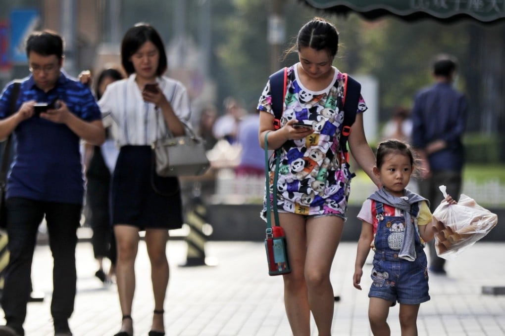 Pedestrians view their smartphones as they walk along a sidewalk in Beijing, Wednesday, Aug. 9, 2017. China has one of the world's largest mobile phone market and become more and more popular among all different ages of people in China. Photo: AP