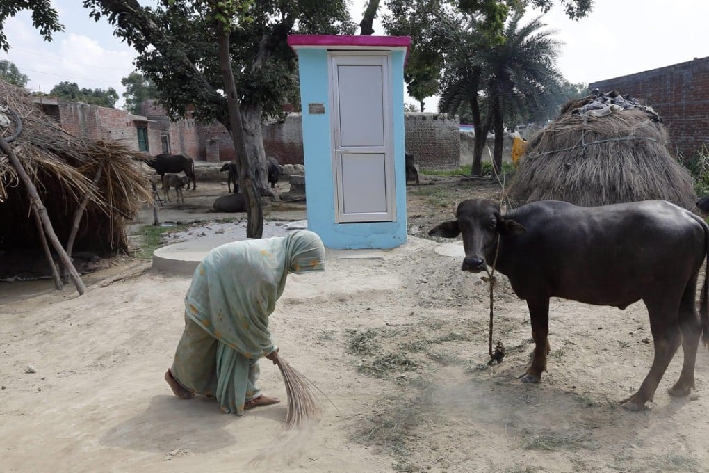 A woman brushes the ground near new toilet in Katra village in Badaun, Uttar Pradesh. Photo: EPA