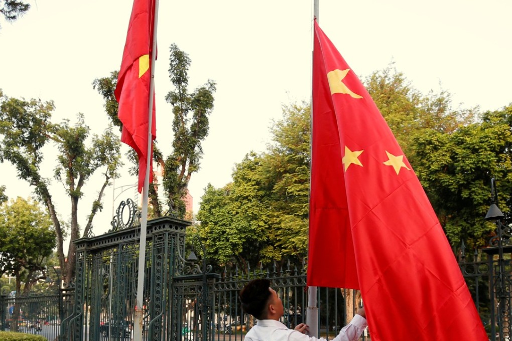 A man raises a Chinese flag, right, next to a Vietnamese flag before a summit in Hanoi. Photo: Reuters