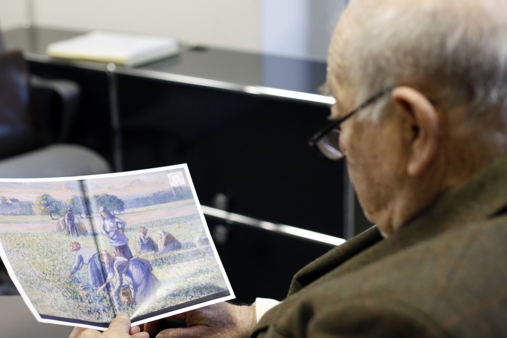 Jean Jacques Bauer, looks at a reproduction of a valuable Pissarro painting he recovered. A Paris court has ordered an American couple to return a valuable Camille Pissarro painting looted during World War II to the descendants of a French family who owned it at the time. Photo: AP