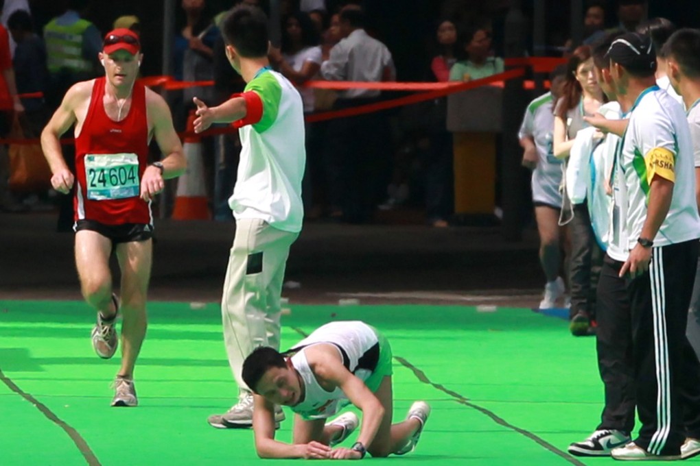 A runner collapses approaching the finish line at Victoria Park in the Hong Kong Marathon. Photo: Felix Wong