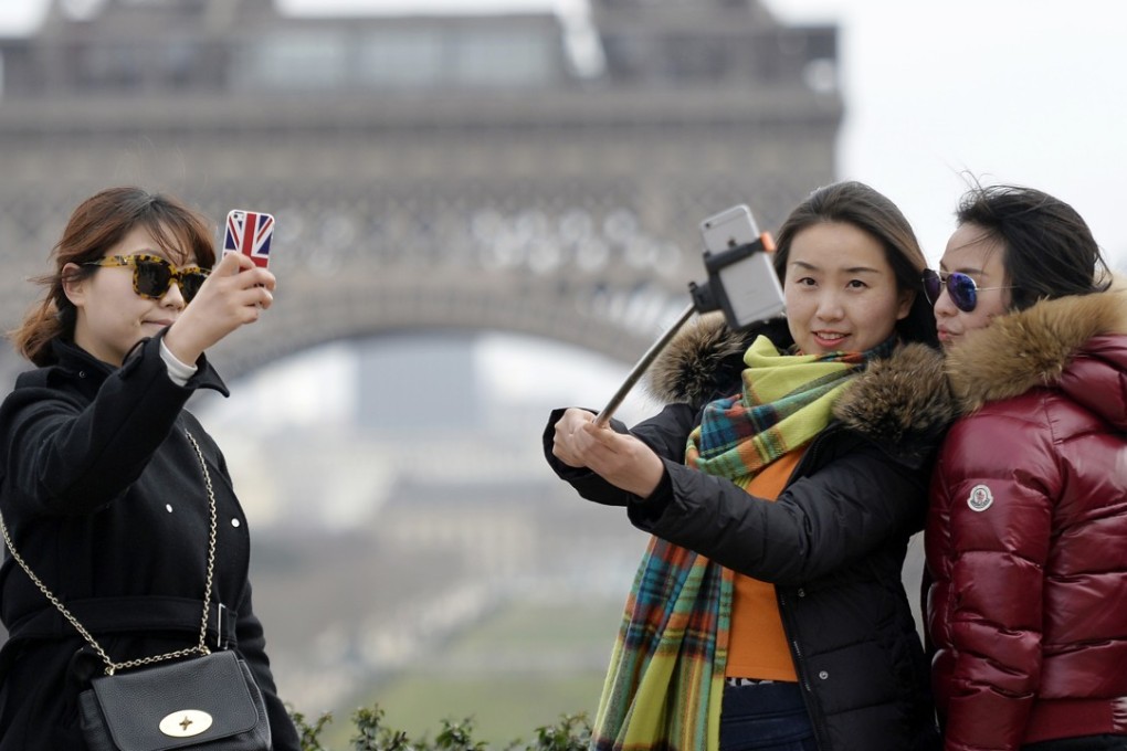 Tourists take selfie near the Eiffel Tower in Paris. Photo: AFP