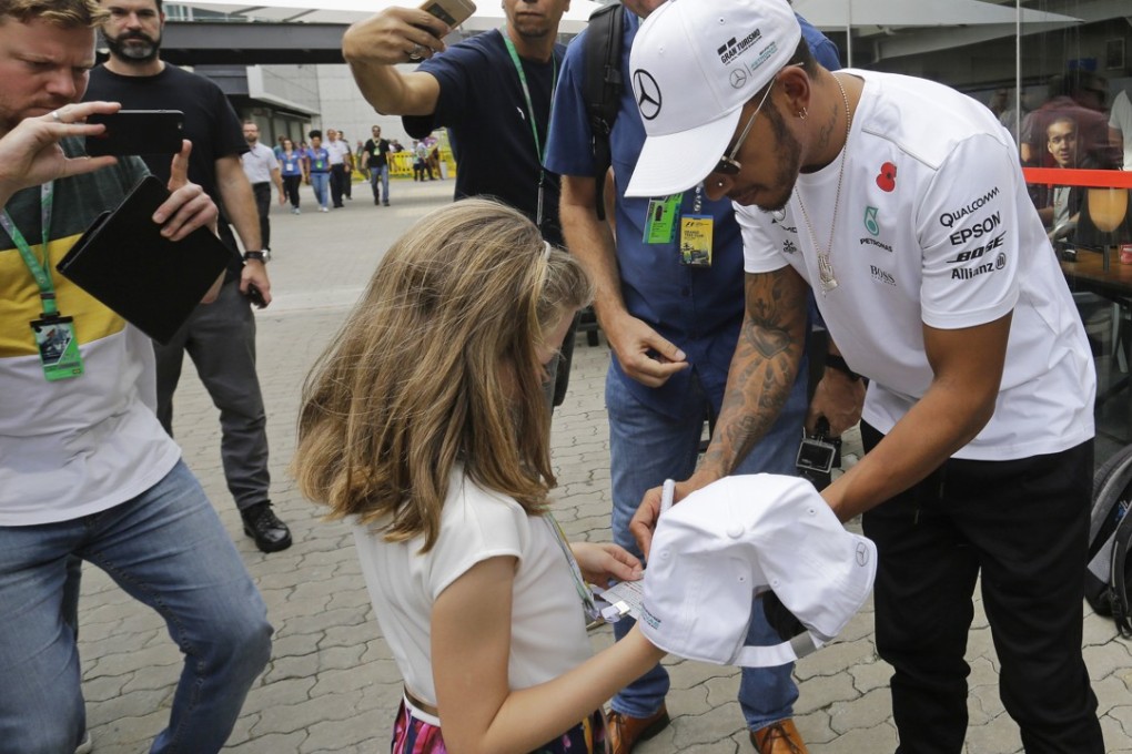 Mercedes driver Lewis Hamilton signs an autograph for a young fan in the paddock area after the second free practice at the Interlagos racetrack in Sao Paulo. Photo: AP