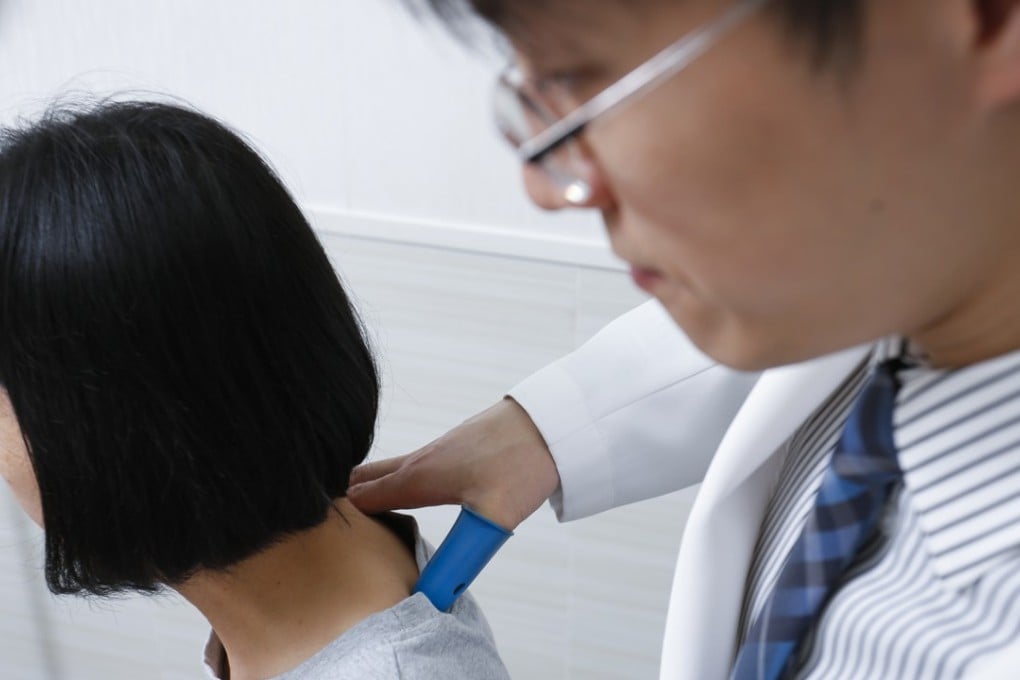 Chiropractor Antonio Wong (right) demonstrates the process of diagnosing frozen shoulder with clinic assistant Connie Choi. Photo: May Tse
