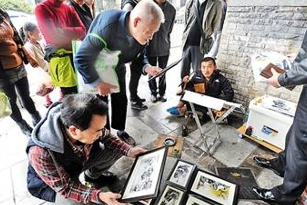 Tang Changyin (seated) pictured selling some of his artwork in Chongqing. Photo: News.china.com