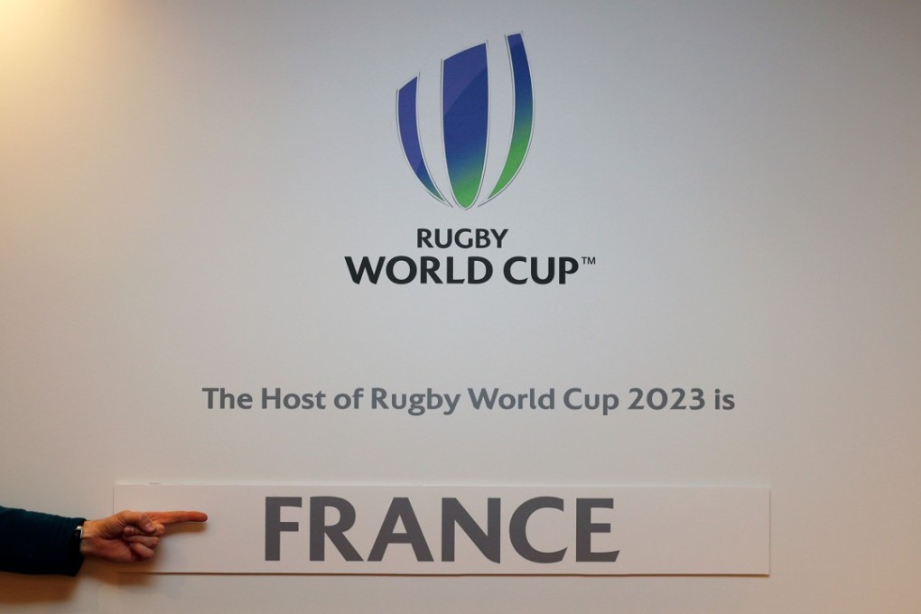 A journalist points to the France sticker attached to the wall after being named host for the 2023 Rugby World Cup in London. Photo: AFP