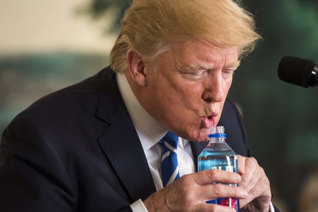 US President Donald Trump uses both hands to drink water while touting his foreign policy accomplishments during his trip to Asia. Photo: EPA