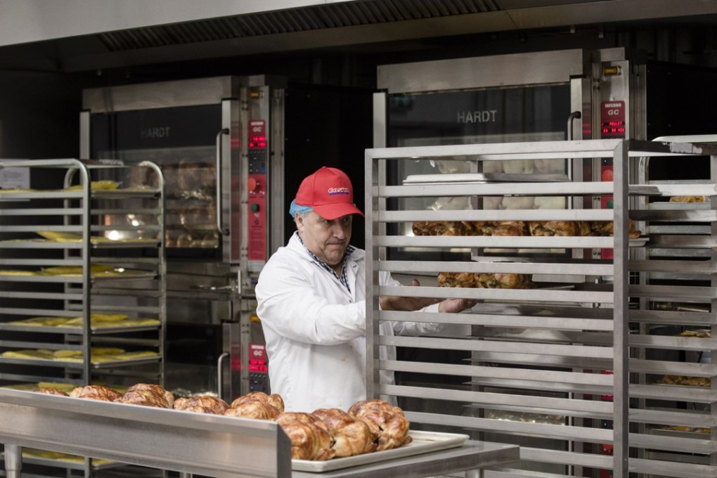 An employee places freshly roasted rotisserie chicken on to a rack inside a Costco Wholesale store in Villebon-sur-Yvette, France. Photo: Bloomberg