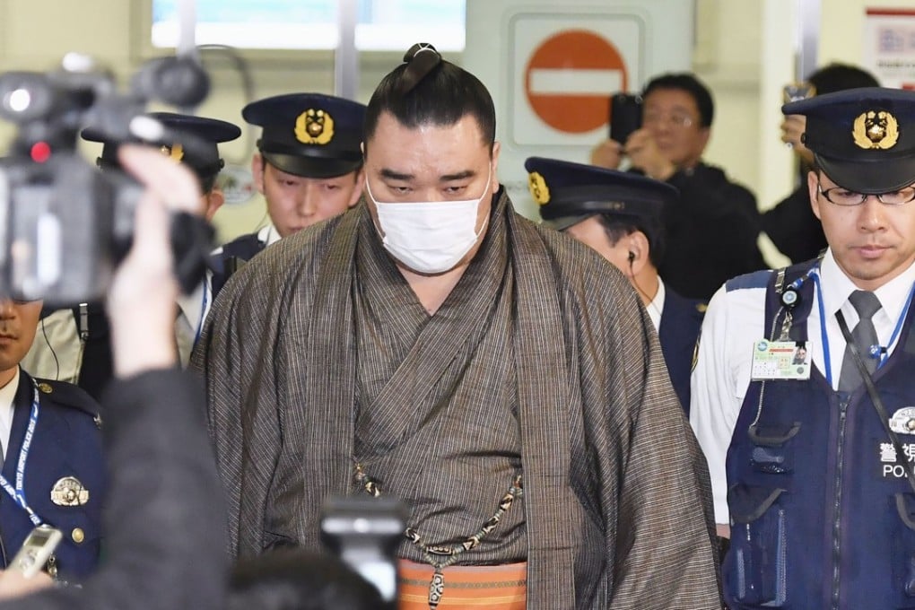 Sumo grand champion Harumafuji is escorted by police at Tokyo's Haneda airport. He is being investigated for allegedly assaulting fellow wrestler Takanoiwa in late October. Photo: Kyodo