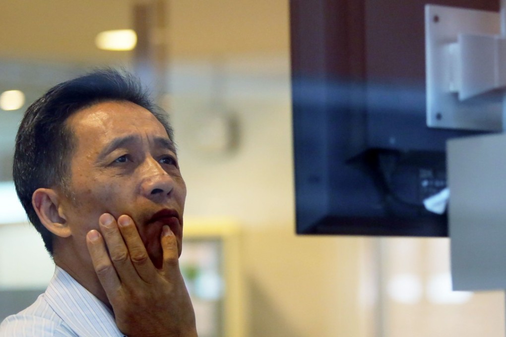 A man looking at an electronic board displaying stock information. Photo: SCMP