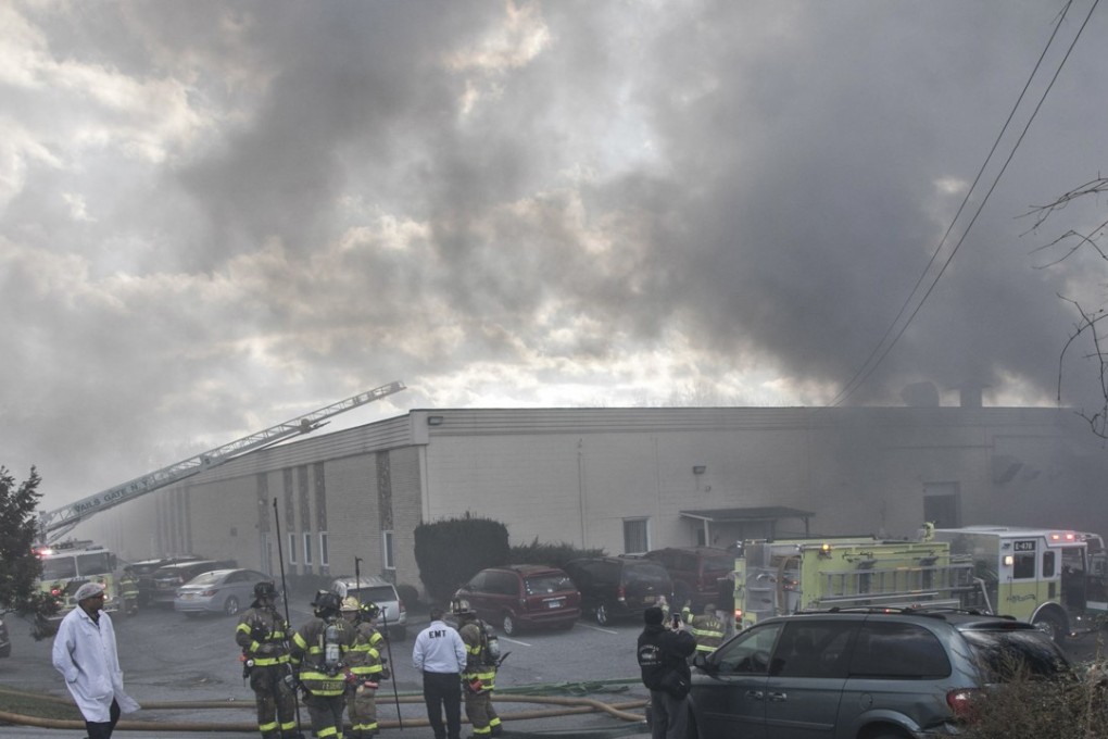 Firefighters remain on the scene of a fire at the Verla International cosmetics factory. Photo: Times Herald-Record via AP