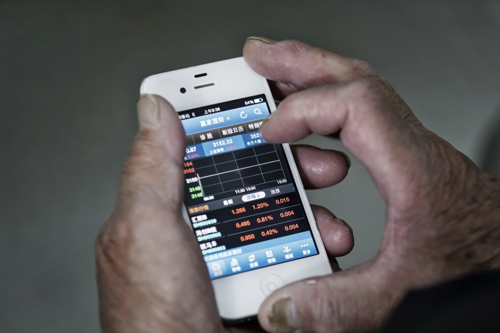 An investor checks share prices in Shanghai. The Shanghai Composite Index was 0.4 per cent higher at the midday break on Tuesday. Photo: Bloomberg