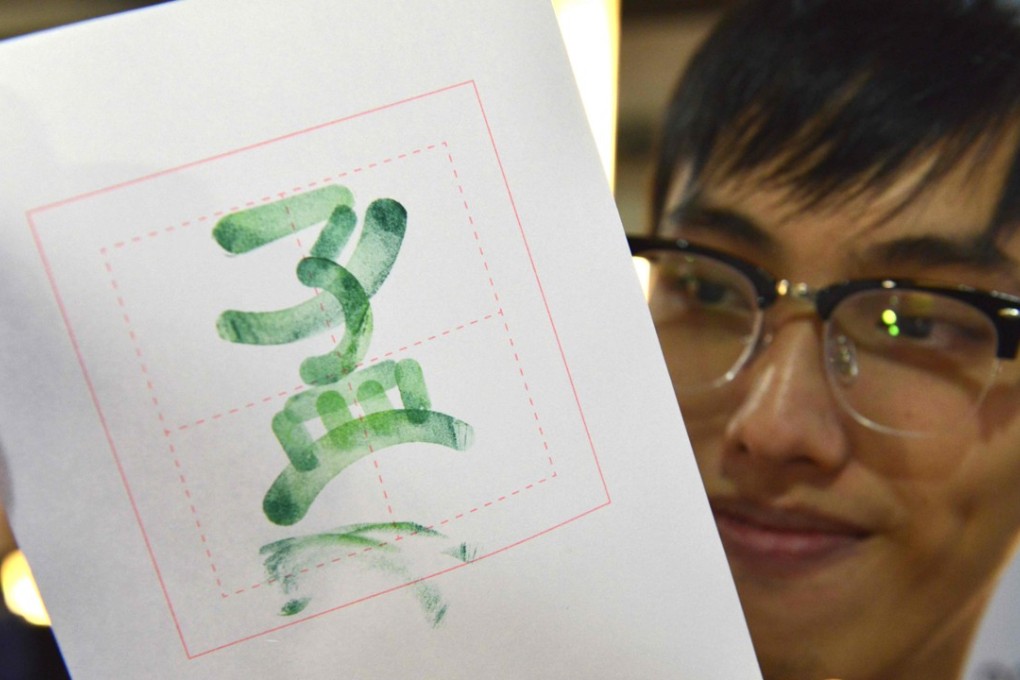A visitor holds up a traditional Chinese character he made using stamps during an educational fair in Taipei last month. Photo: AFP