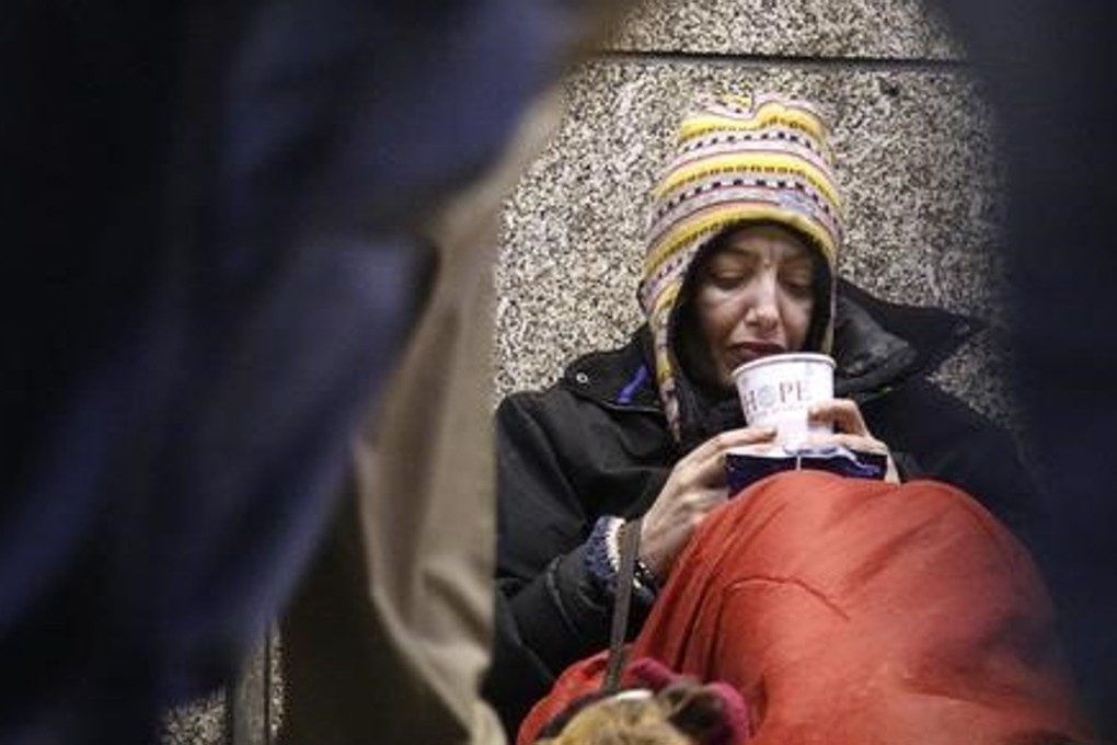 Dawn, a homeless woman from north Wales, sits huddled under a sleeping bag next to her dog Casper in a shopping arcade near the Victoria rail station in central London. Photo: Reuters