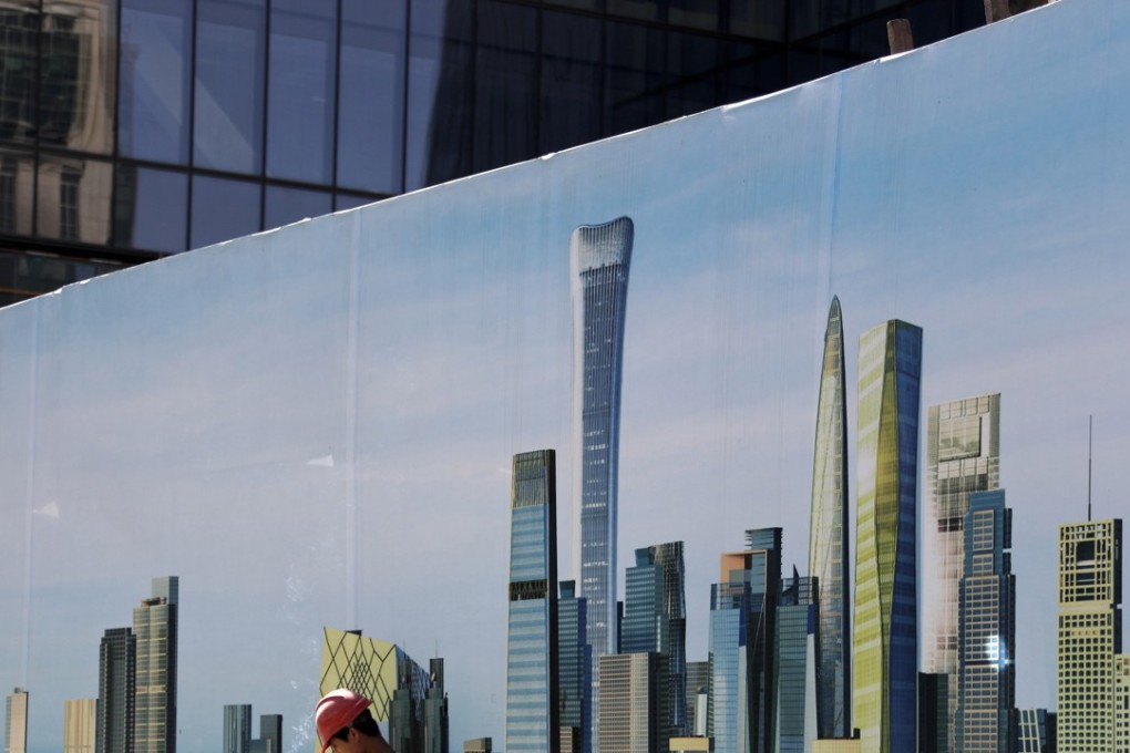 A worker smokes while checking on his mobile phone at a construction site wall depicting the skyscrapers in the Chinese capital at the Central Business District in Beijing, Tuesday, Sept. 19, 2017. Photo: AP