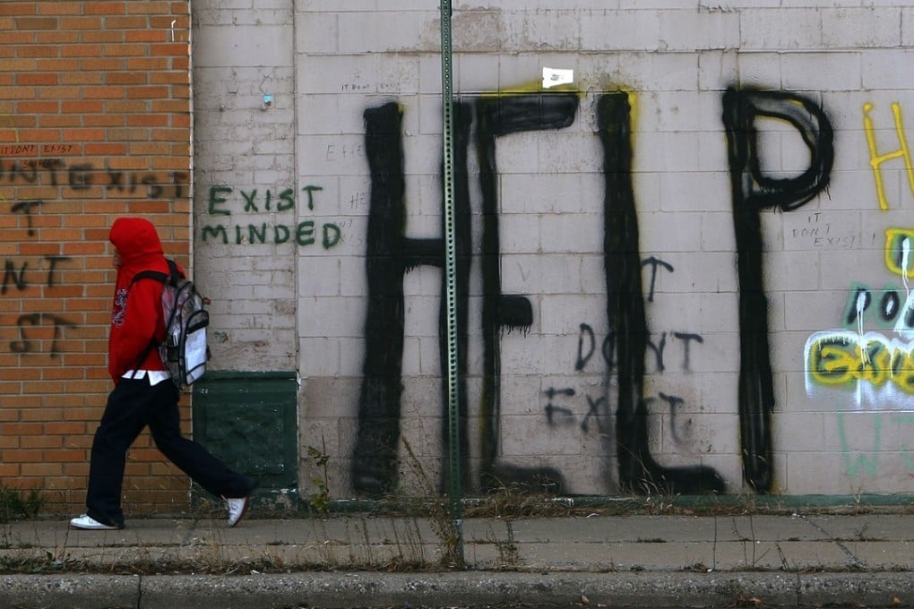 A pedestrian walks by graffiti on a Detroit street. Photo: AFP