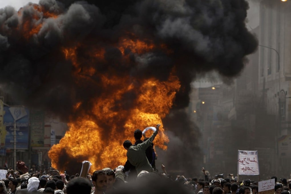 Yemeni anti-government demonstrators react after setting on fire a vehicle belonging to supporters of President Ali Abdullah Saleh during clashes in Sanaa, Yemen. Saleh was killed on Monday, December 4, 2017, by Shiite rebels with whom he had once been allied. His death sparked fears of an escalation in fighting. Photo: AP