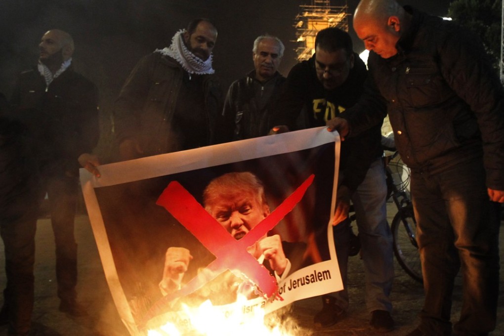 Palestinian protesters burn pictures of US President Donald Trump at the manger square in Bethlehem on Tuesday. Photo: AFP