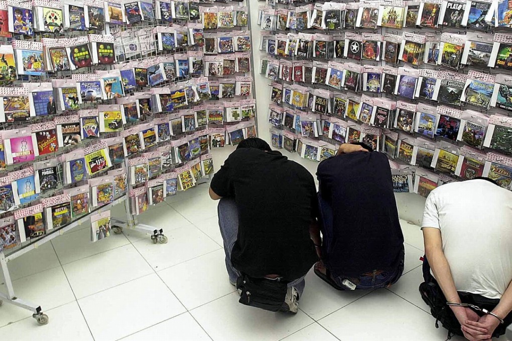 Three man arrested for selling pirated cd's squat in the shop in Singapore. Photo: AFP