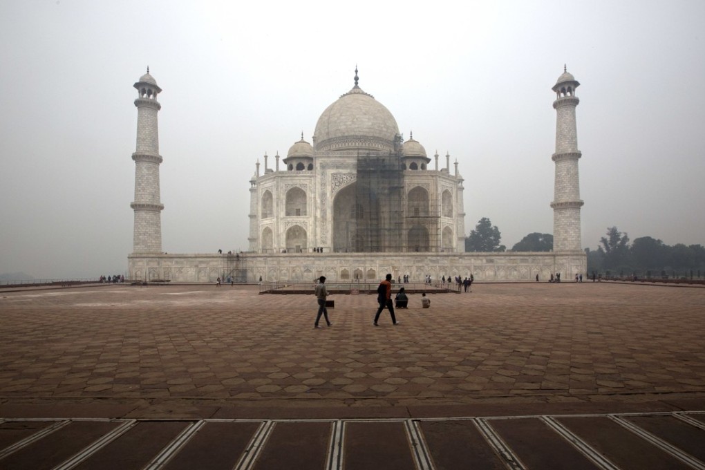 Tourists walk around the Taj Mahal as workers clean the monument in Agra, India. Photo: AP