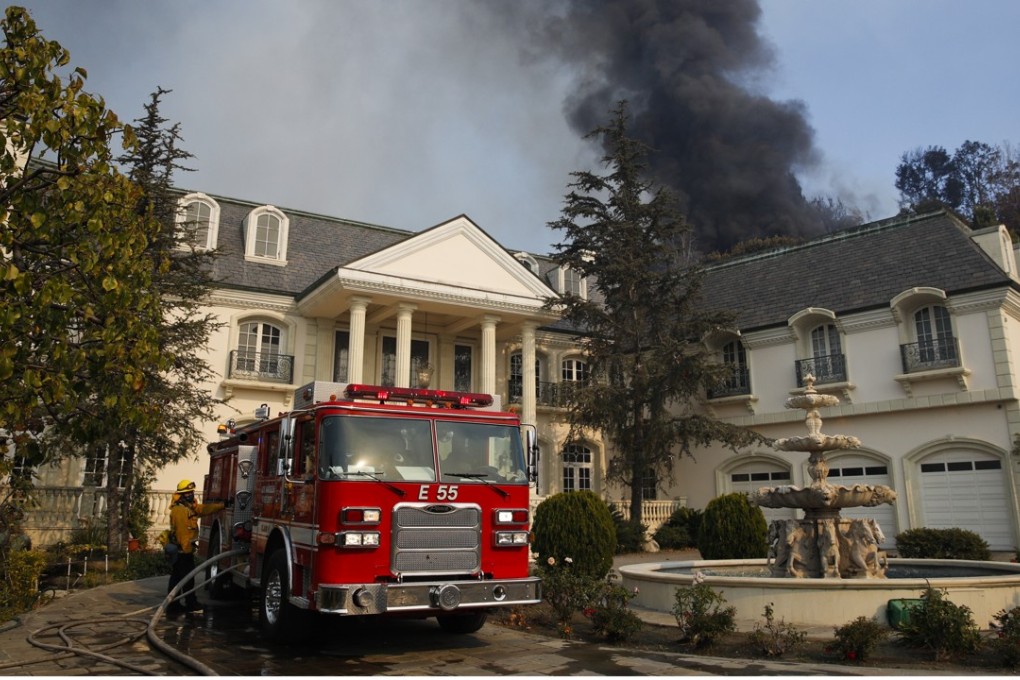 A fire truck is parked outside a mansion as smoke from a fire rises behind the property Wednesday in the Bel-Air neighbourhood of Los Angeles. Photo: AP