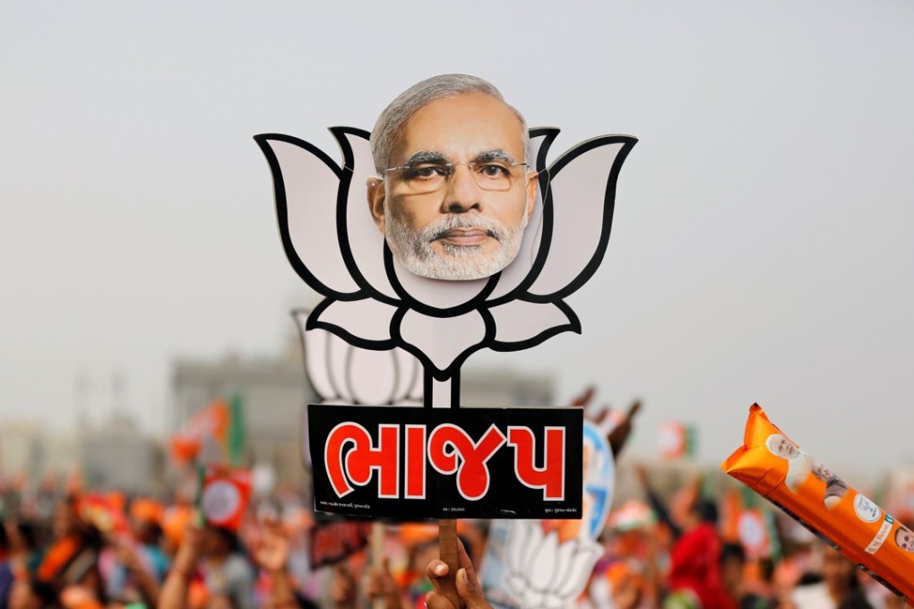 A supporter holds up a cut-out of a lotus, the election symbol of India’s ruling BJP with an image of Prime Minister Narendra Modi stuck on it. Photo: Reuters