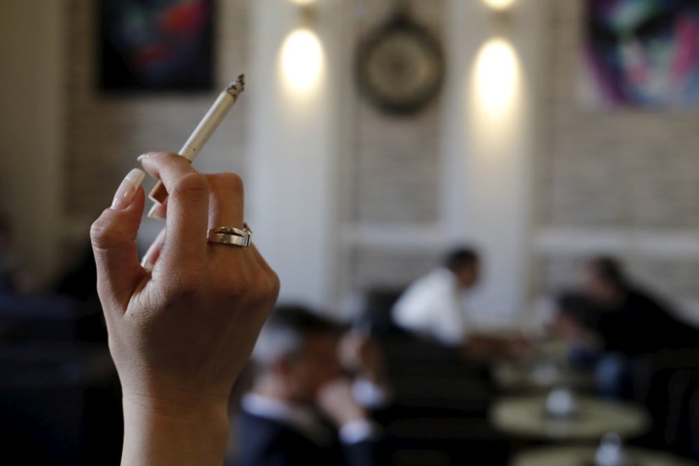 A woman holds a cigarette in a cafe in Vienna. Photo: Reuters