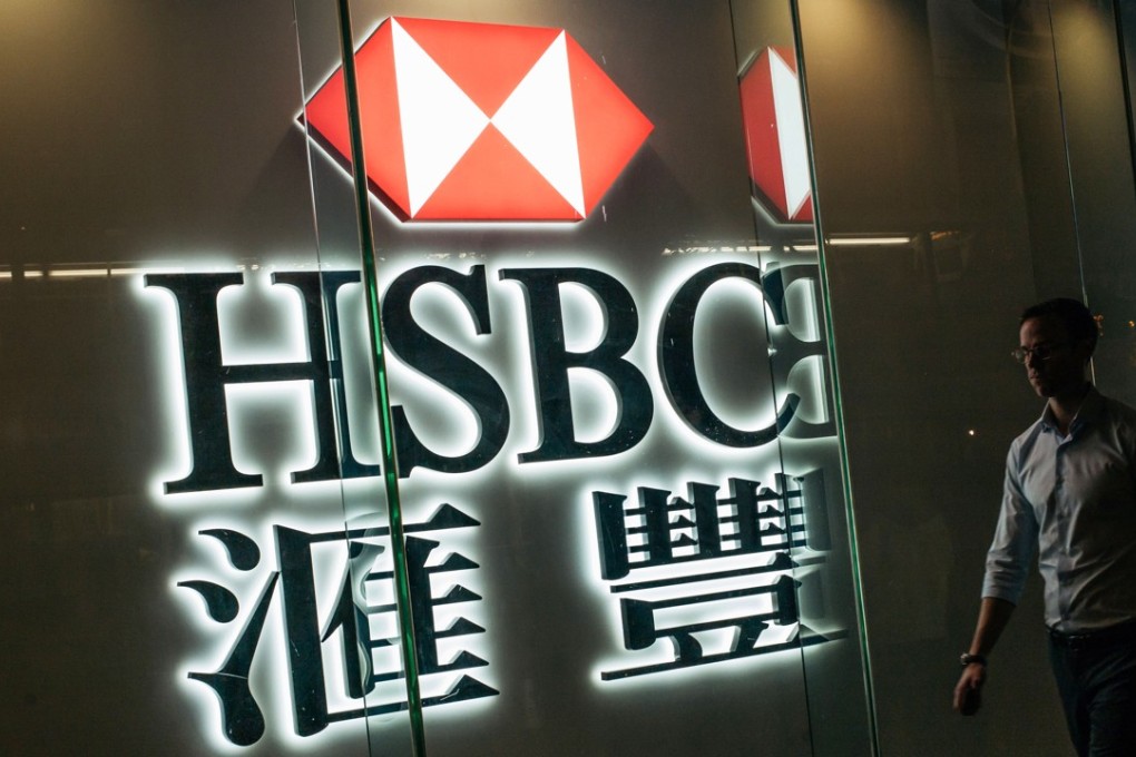 A pedestrian walks past illuminated signage for HSBC. Photo: Bloomberg
