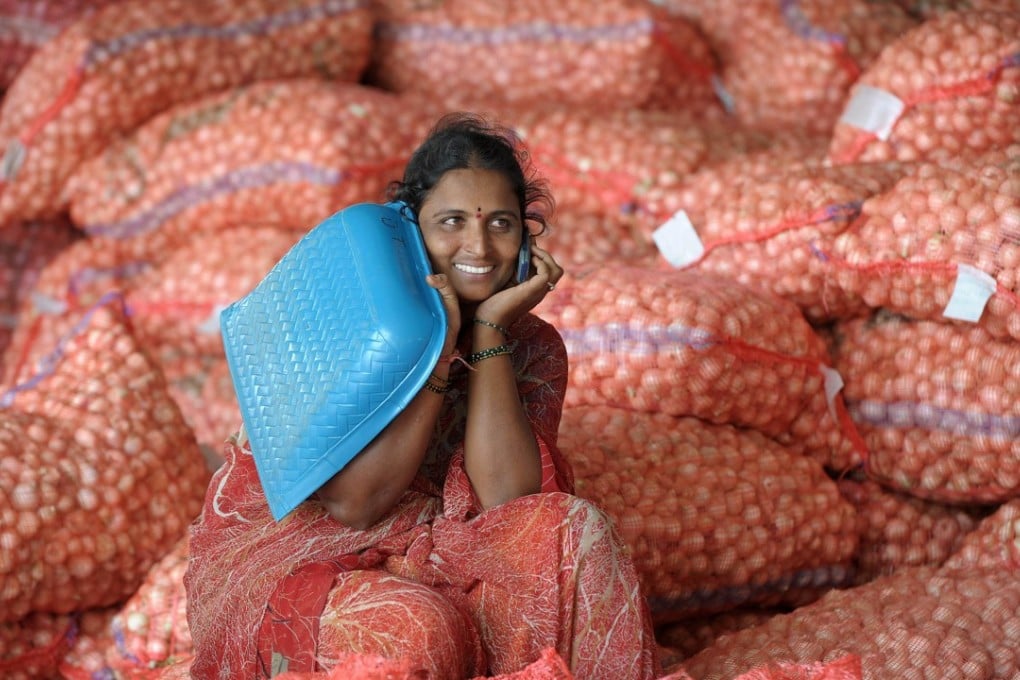 Indian labourers speaks on a cellular telephone as she sits on onion bags at a wholesale market yard in Hyderabad on August 17, 2013. Photo: AFP