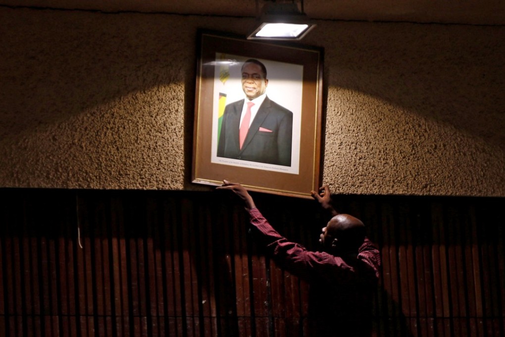 An official puts up a portrait of Zimbabwe’s President Emmerson Mnangagwa ahead of a meeting of the ZANU-PF central committee in downtown Harare on Thursday. Photo: Reuters
