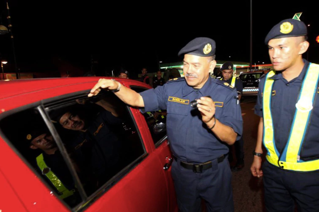 Negri Sembilan Road Transport Department (RTD) assistant director Rosilan Md Saari (left) inspects one of the tinted cars at Jalan Seremban - Tampin. Deputy Transport Minister Datuk Abdul Aziz Kaprawi says foreign vehicles with dark window tints will not be allowed to enter Malaysia. Photo: HAZREEN MOHAMAD/New Straits Times