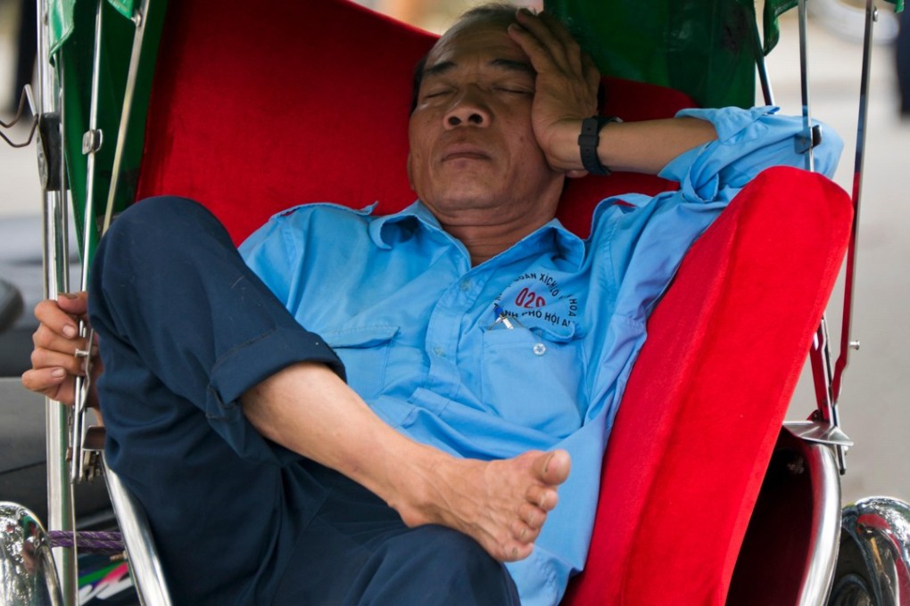 A cyclo driver recharges with a quick nap on the job in Hoi An, Vietnam.