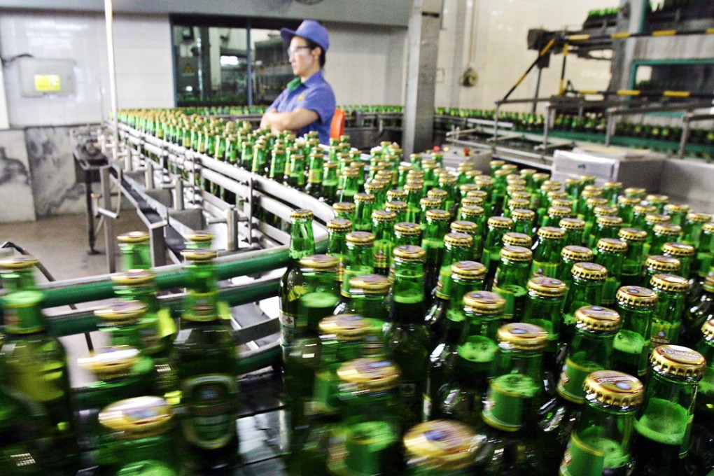 A worker inspects bottles of Tsingtao beer rolling out from one of the four breweries in the eastern Chinese port city of Qingdao in August 2006. Tsingtao, which dates back to 1903 when Qingdao was still a German treaty port, has expanded aggressively over the past 14 years, growing from four plants in its home province of Shandong in the east to 50 subsidiaries around the country. Photo; AFP