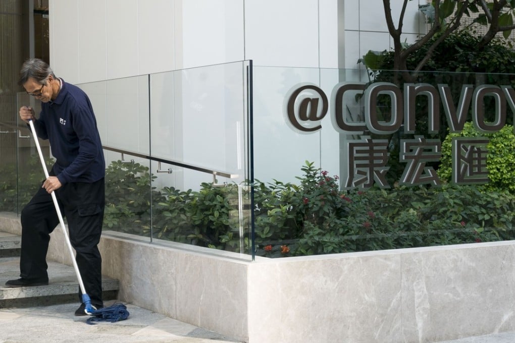 A man mops the floor outside the "@Convoy” building, which houses the headquarters of Convoy Global Holdings, in Hong Kong on December 11. Convoy has confirmed that three executive directors were arrested by the anti-corruption agency, including Chairman Wong Lee Man. Photo: Anthony Bloomberg