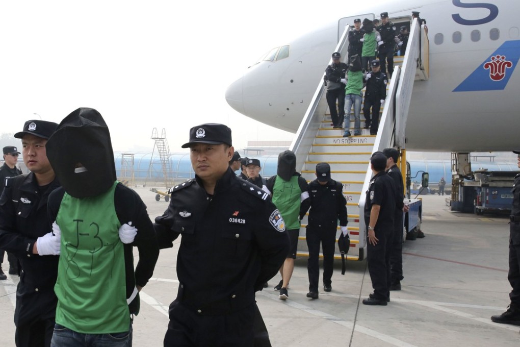 Suspects involved in telecoms fraud are escorted off a plane in Beijing last year. They were tried in mainland China after being deported from Kenya. Photo: AP