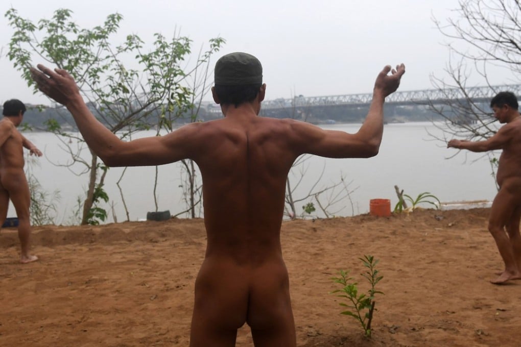 Nudists warming up for a swim by the southern banks of the Red River in Hanoi. Photo: AFP