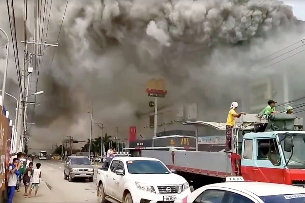 People watch as smoke rises from the shopping centre third floor. Photo: Reuters