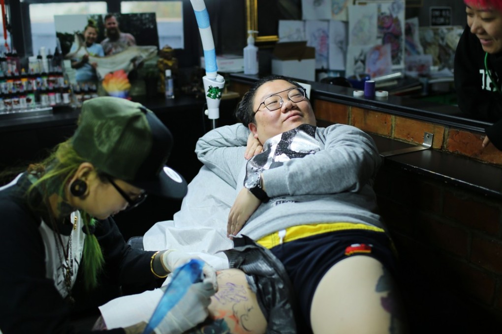 Wang Yi (centre), a web designer and tattoo enthusiast, gets new design on her right thigh at a studio in Shanghai. Photo: Agence France-Presse