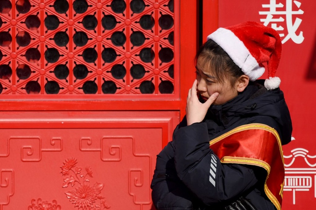 A tour guide wears a Santa hat while waiting for customers at the entrance of a restaurant in Beijing on December 25, 2017. Photo: AFP