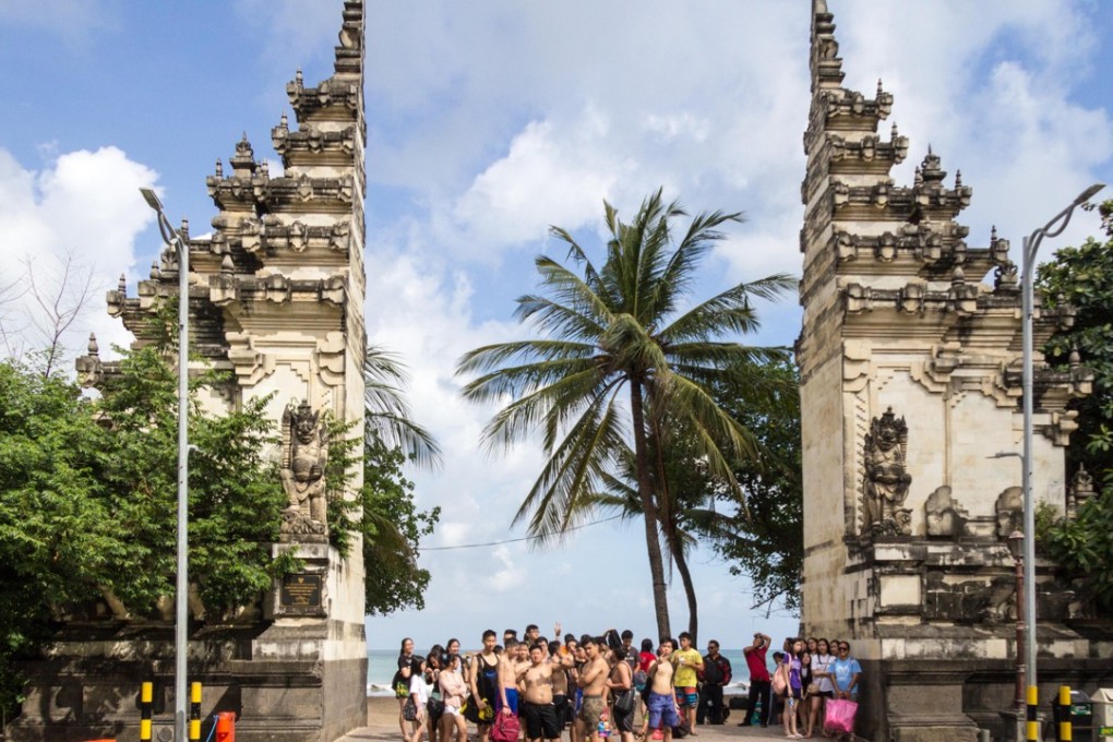 Chinese tourists at the entrance to Kuta Beach in Bali. Photo: Alamy