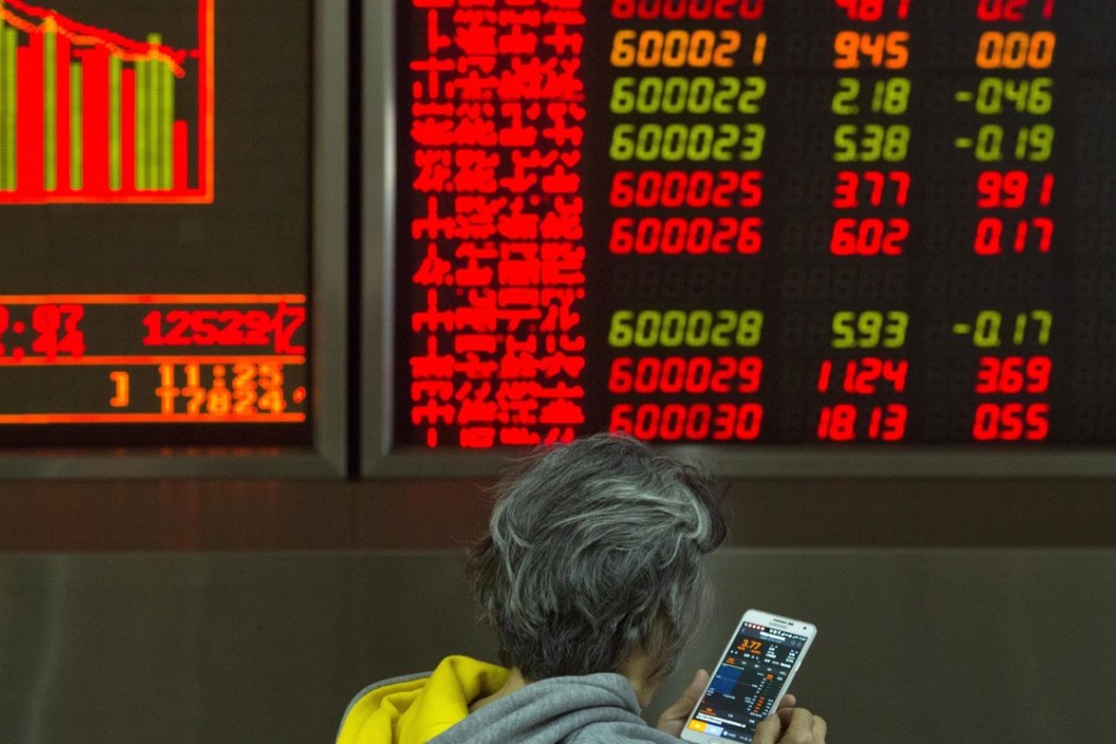 An investor looks at the stock price on her mobile phone near a display board at a brokerage in Beijing. Photo: AP