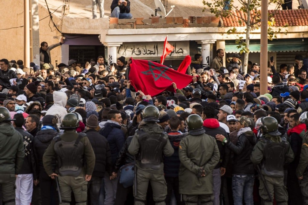 Moroccans shout slogans and wave a national flag as they participate in a demonstration after the funeral of two brothers who died while working in an abandoned coal mine in the northeastern city of Jerada. Photo: Agence France-Presse