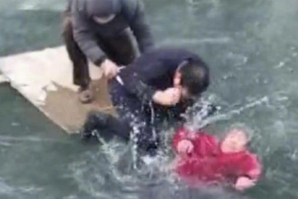 A man smashes the ice to free the woman, while another bystander grabs his clothes to stop him falling into the freezing water. Photo: Weibo